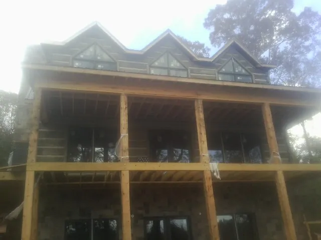 Dormers and porch framing on a large log home under construction — Roof Coating work by our crew in Sharon Grove