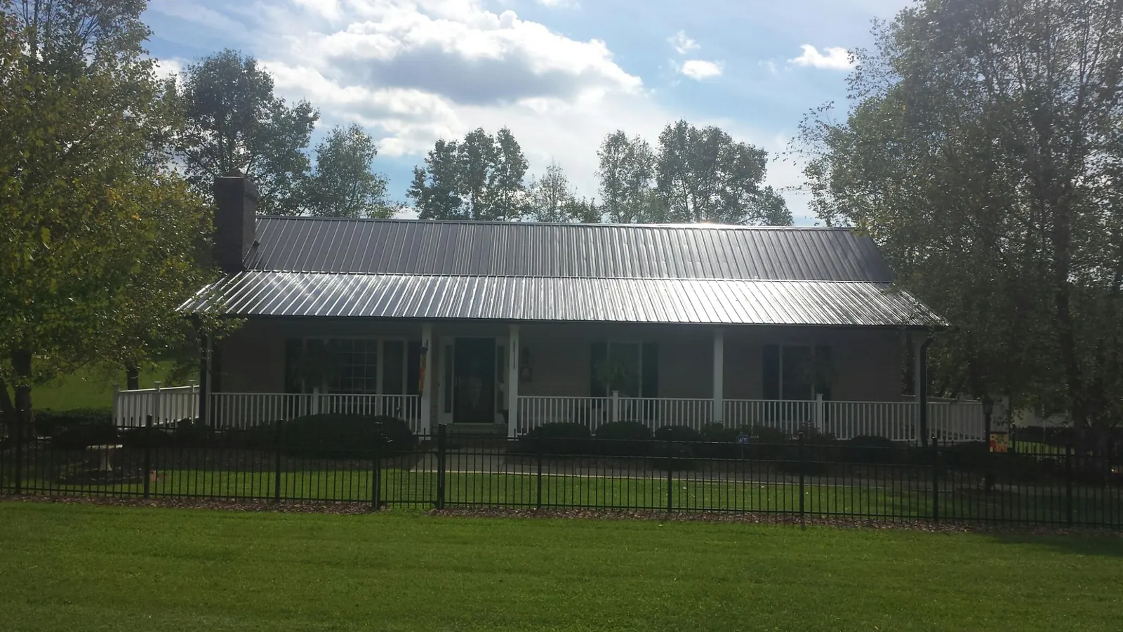 Gray metal roof on a brick ranch with a full width front porch — Gutter Guard Installation work by our crew in Sharon Grove
