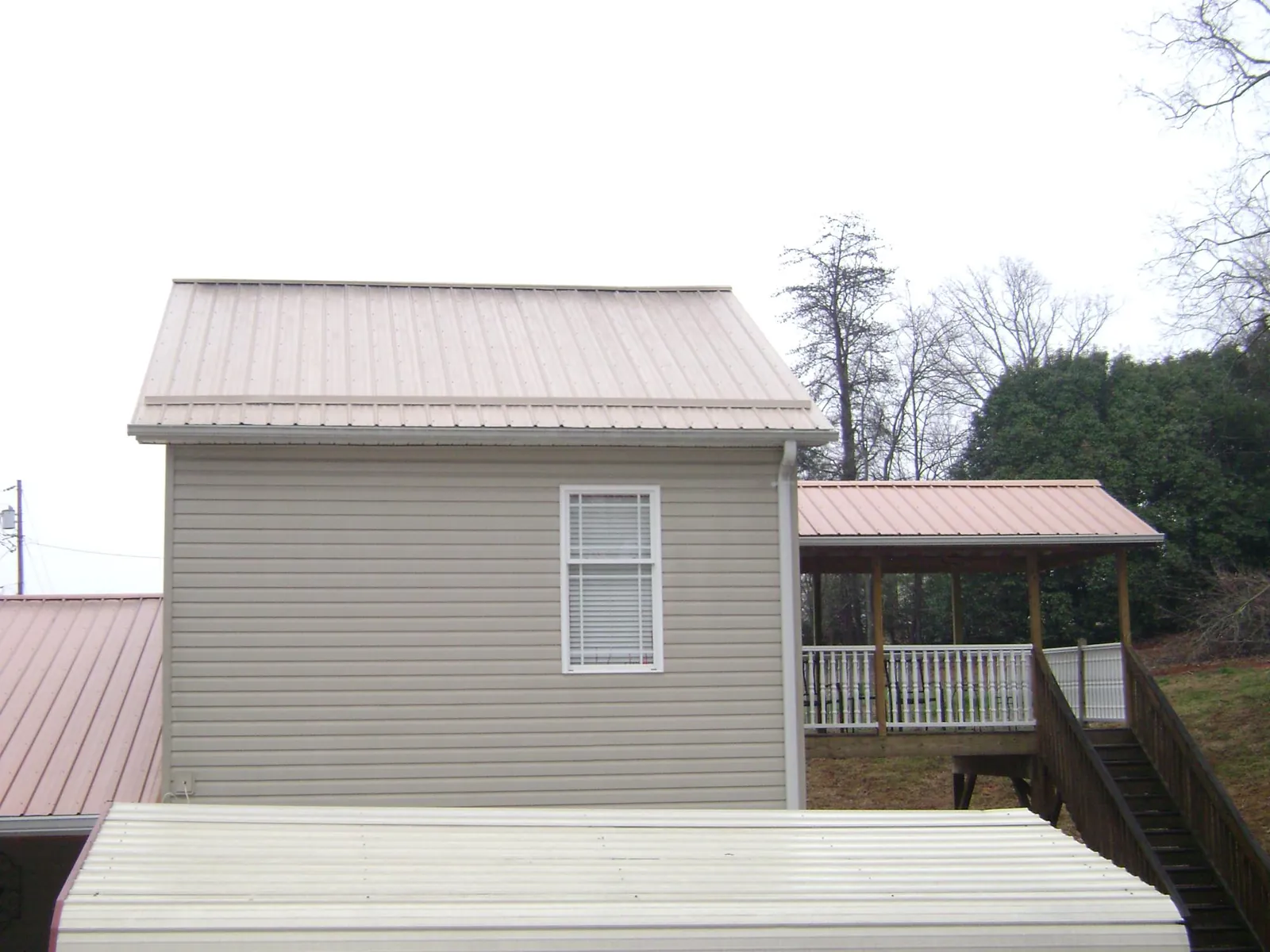 Tan metal roofs on a two story addition and attached porch, from a Roof Replacement job in Sharon Grove