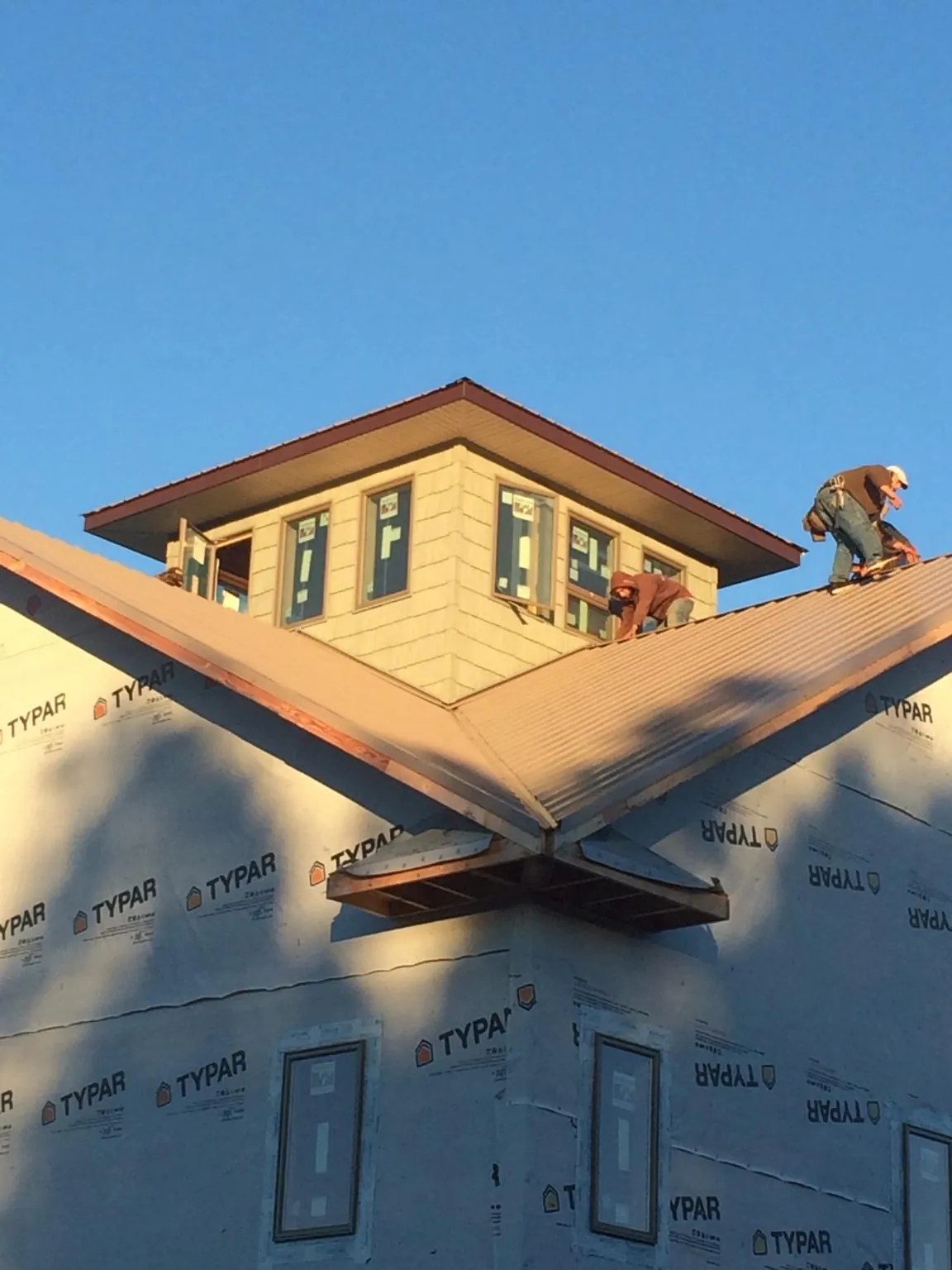 Roofers working around a rooftop cupola on a new metal roof at sunset — Roof Waterproofing in Sharon Grove by Roofing Brothers